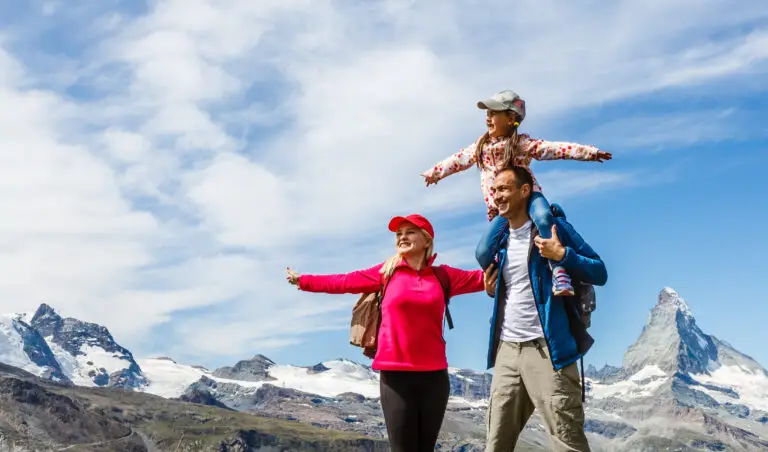 Happy family with little child doing trekking on switzerland mountain in summer time. Young people having fun in landscape nature. Concept of travel, friendly family.
